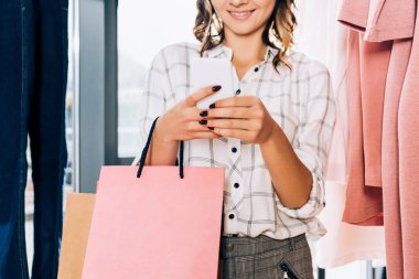cropped shot of stylish woman using smartphone on shopping