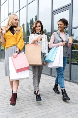 güzel genç kadın alışveriş torbaları ve kahve ile gitmek için grubu