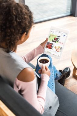 beautiful young woman using tablet with ebay website on screen