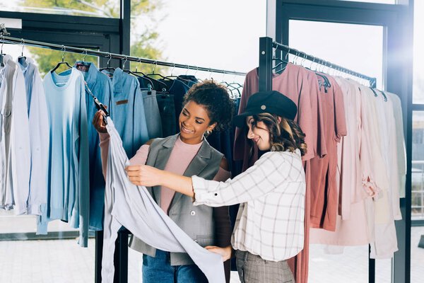 молодые стильные покупатели смотрят на новую рубашку в магазине одежды
