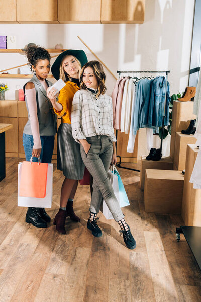group of stylish young women taking selfie in clothing store