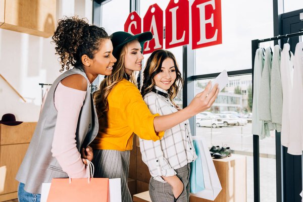 group of multiethnic young women taking selfie on shopping