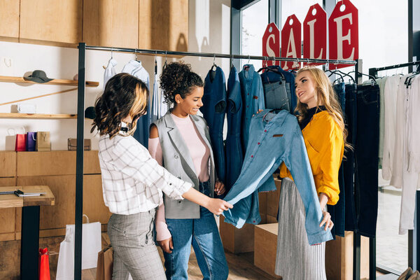 group of multiethnic shopaholics on shopping in clothing store