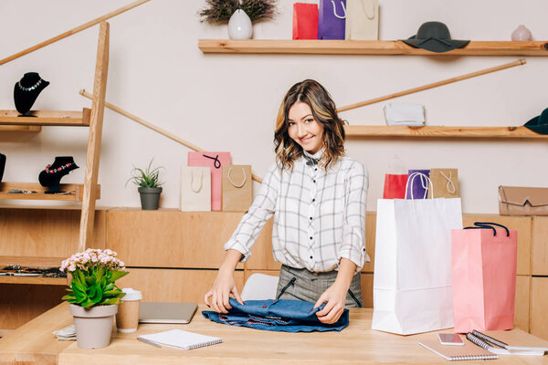 clothing store manager folding shirt to pack it into shopping bag