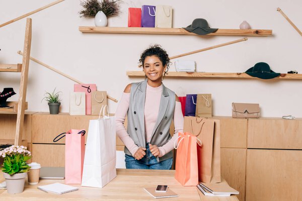 clothing store manager standing at workplace with shopping bags on table