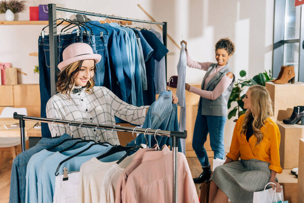group of stylish young women on shopping in clothing store