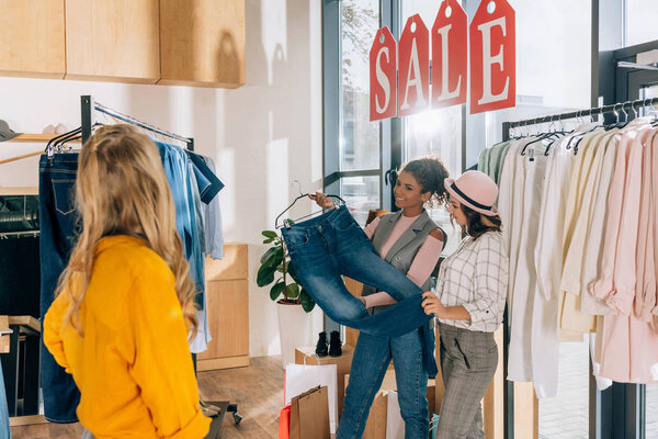 group of young shopaholics in clothing store on sale