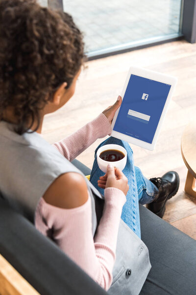 beautiful young woman using tablet with facebook on screen