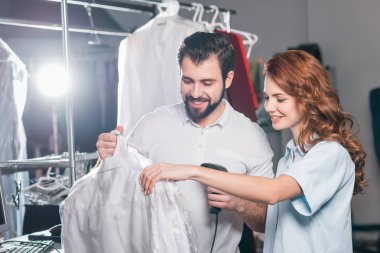 young dry cleaning workers scanning barcode on bag with shirt clipart