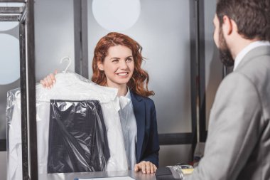 dry cleaning manageress holding bag of clothes for customer clipart