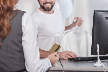 cropped shot of woman giving credit card to dry cleaning manager  clipart