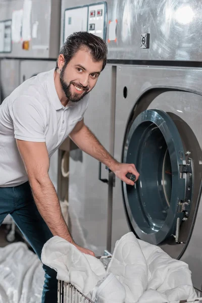 dry cleaning worker opening industrial washing machine