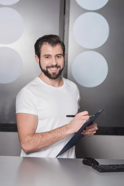 Guapo Joven Gerente Sentado Lugar Trabajo Escritura Portapapeles — Foto de stock gratis