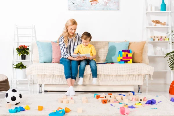 年幼的母亲和儿子在沙发上一起画画 在家里休息 — 图库照片
