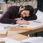 Överarbetade ung arkitekt sover på byggplaner på arbetsplatsen