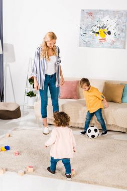 neşeli anne ve sevimli küçük çocuklar evde futbol topu ile oyun