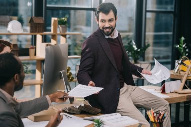 Bina planları ve modern ofis belgeleri tartışırken çok ırklı mimarlar