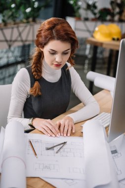 young beautiful businesswoman sitting  looking at papers on table clipart