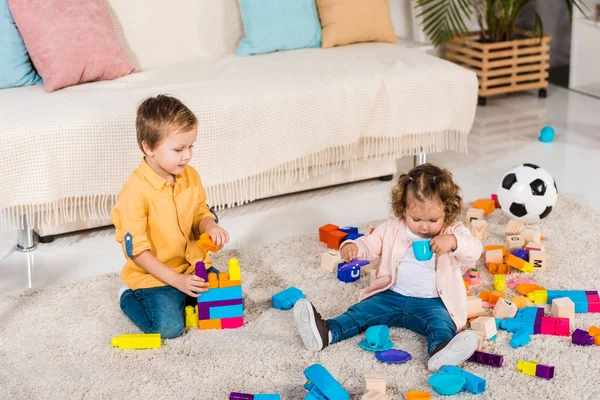 Entzückendes Geschwisterpaar Spielt Mit Plastikklötzen Auf Dem Boden — Stockfoto