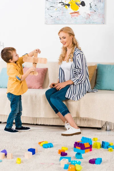 Mère Heureuse Assise Sur Canapé Regardant Mignon Petit Fils Jouer — Photo gratuite