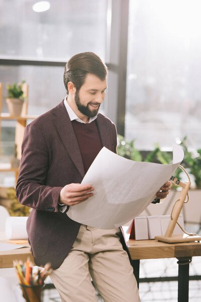 handsome architect looking at blueprint in modern office  