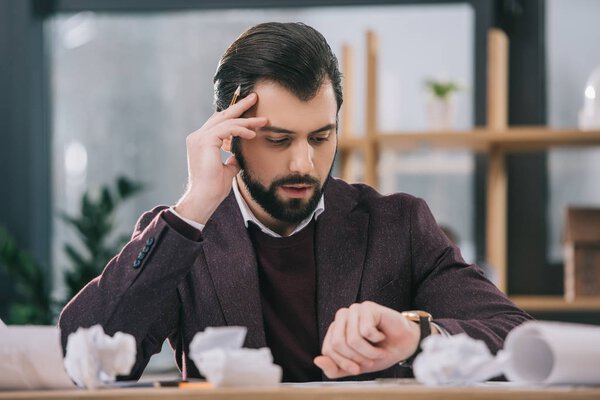 worried architect drawing building plans at workplace with crumpled papers