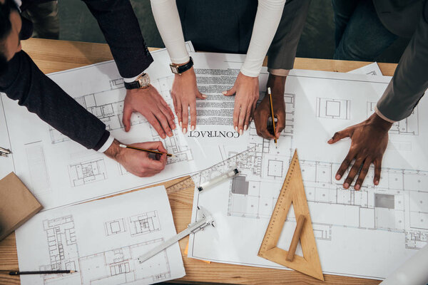 cropped shot of team of architects with building contract and plans