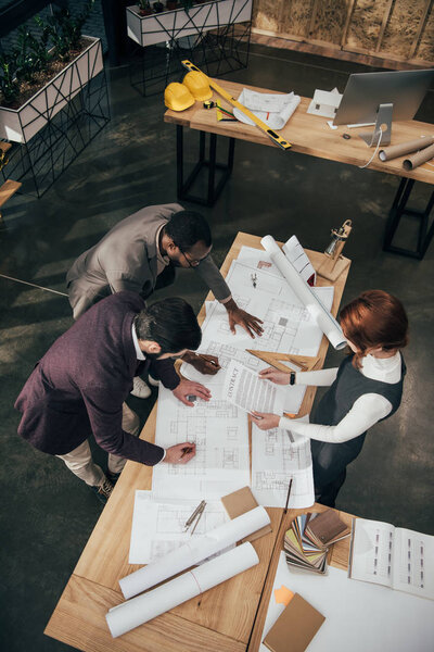 high angle view of team of architects working with architectural plans at office