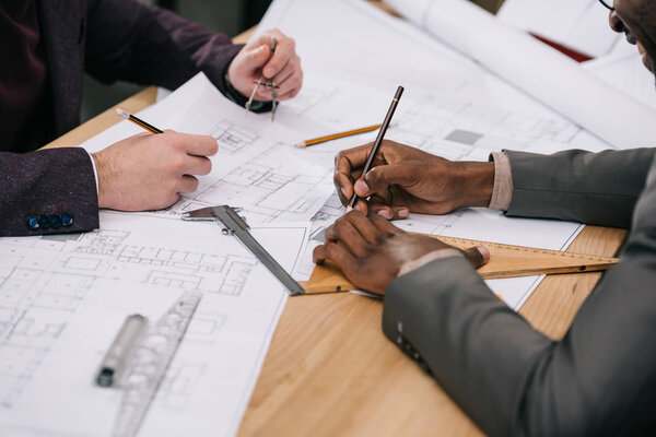 cropped shot of architects drawing architectural plans together
