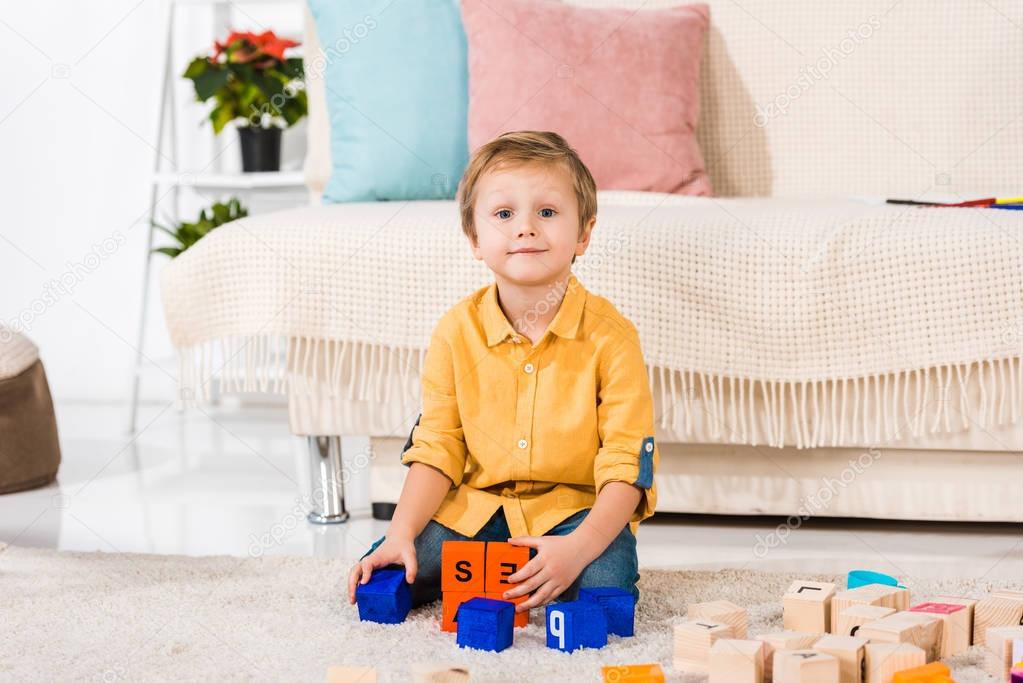 little boy looking at camera while playing with toys at home