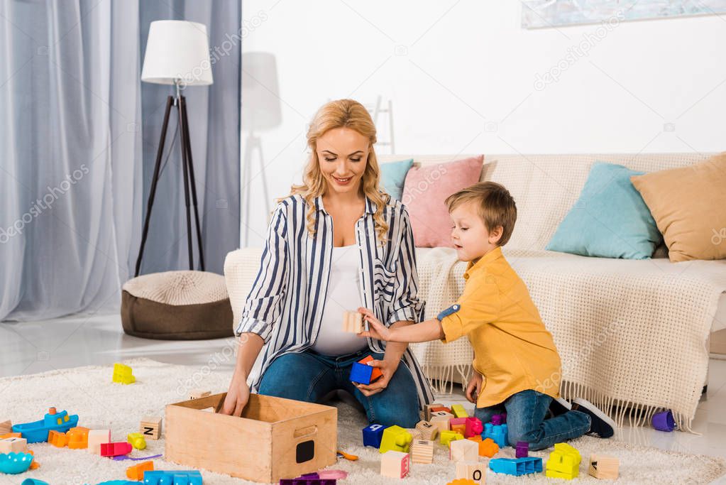 son showing wooden cube to smiling mother