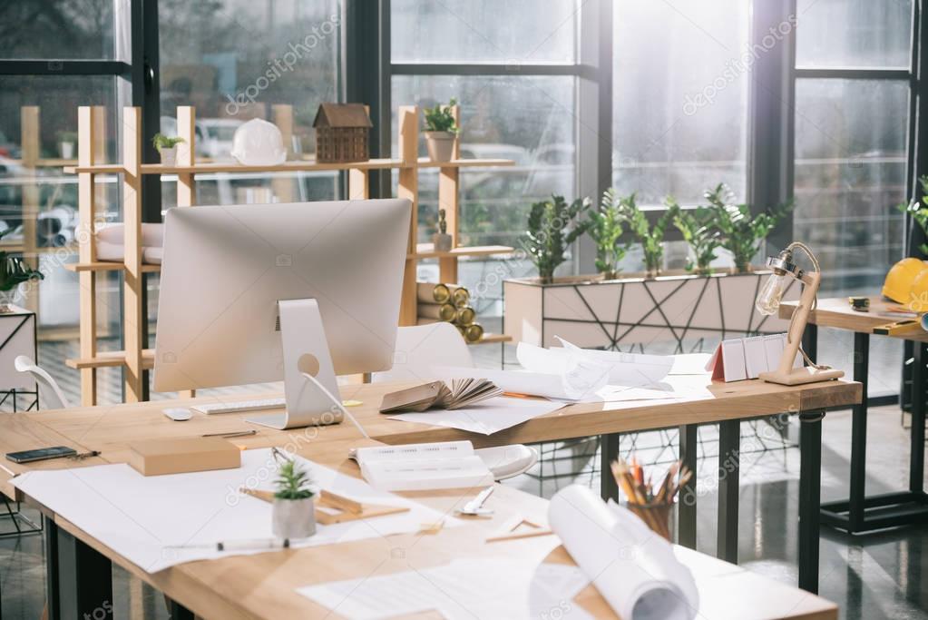 blueprints, documents and computer at workplace in architect office  