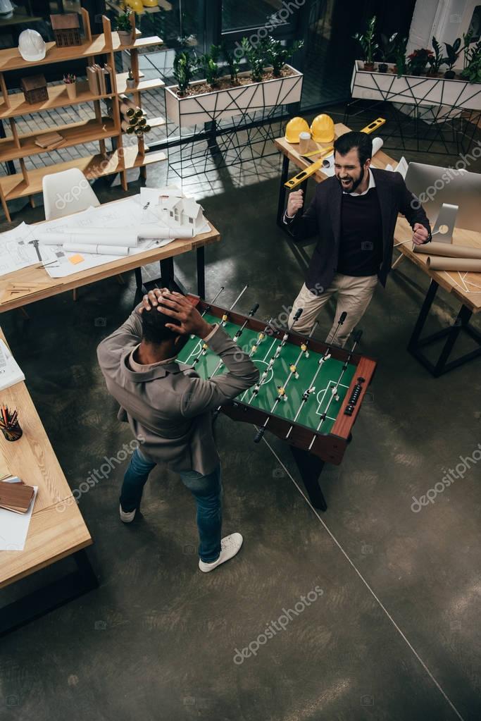 High angle view of young architects playing table football in office