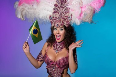 Pembe Tüylü Brasil üzerinde mavi arka plan izole bayrağı tutarak karnaval kılık neşeli kadın