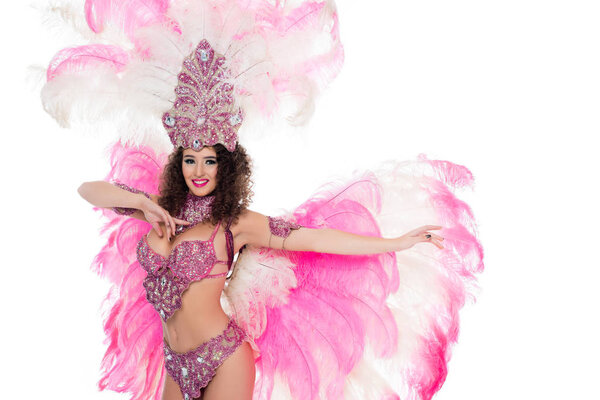 соблазнительная девушка, танцующая в карнавальном костюме с розовыми перьями, изолированная на белом
