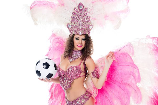 smiling woman in carnival costume with pink feathers holding soccer ball, isolated on white