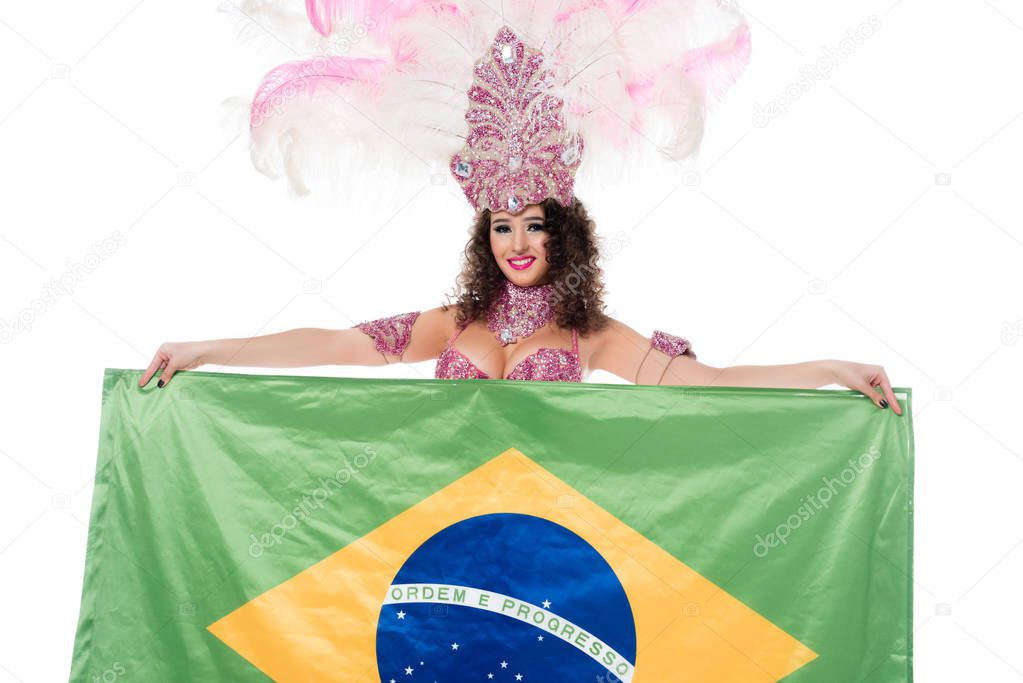 Cheerful woman in carnival costume with pink feathers holds flag of Brasil isolated on white