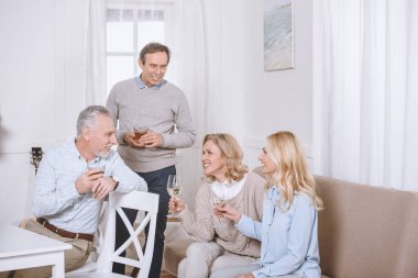 Odada konuşurken kanepe ve sandalye üzerinde oturan arkadaşlar 