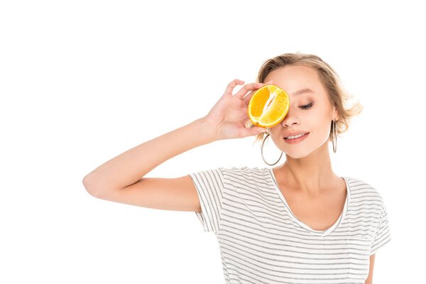 attractive young woman holding half of orange near face isolated on white