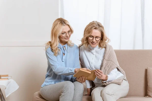 Dos Mujeres Mediana Edad Sentadas Sofá Leyendo Libro —  Fotos de Stock