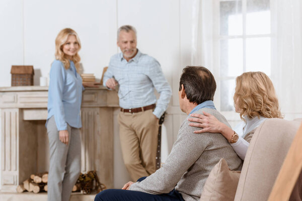 Adult men and women having friendly conversation in living room