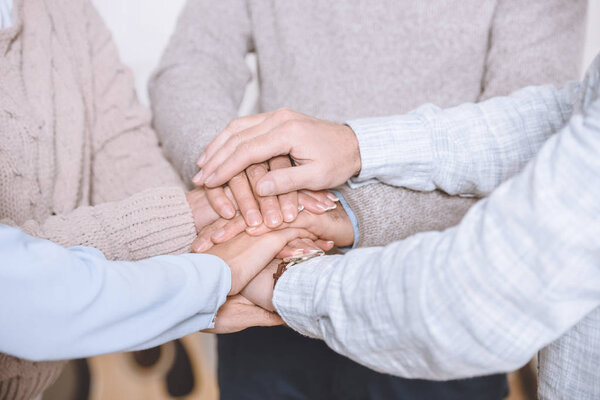 Close-up view of men and women stacking hands together