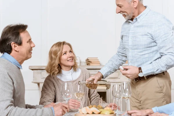 Älterer Mann Mit Flasche Der Hand Steht Gegen Sitzendes Ehepaar — Stockfoto