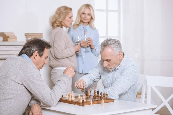 Hombres Jugando Ajedrez Mientras Están Sentados Mesa Mujer Pie Con — Foto de stock gratis