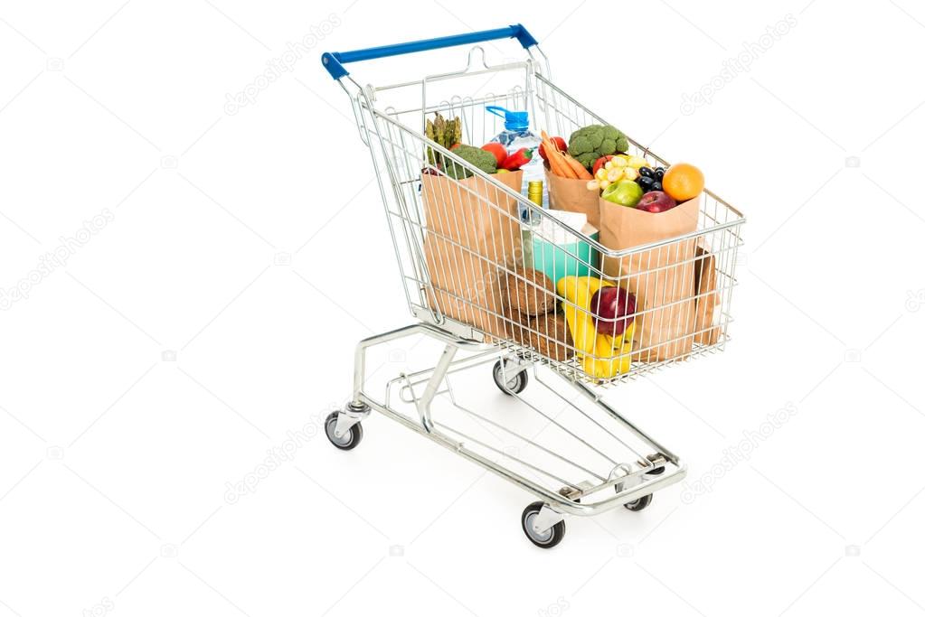 grocery bags in shopping trolley isolated on white