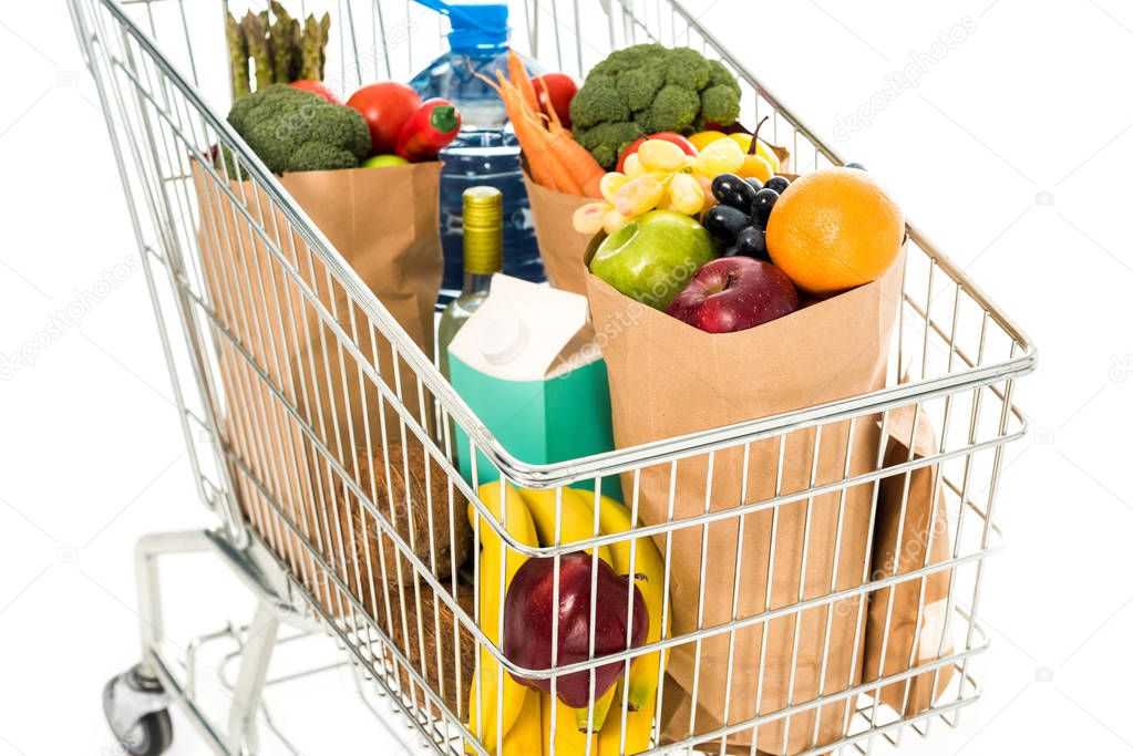 close-up view of full grocery bags in shopping trolley isolated on white