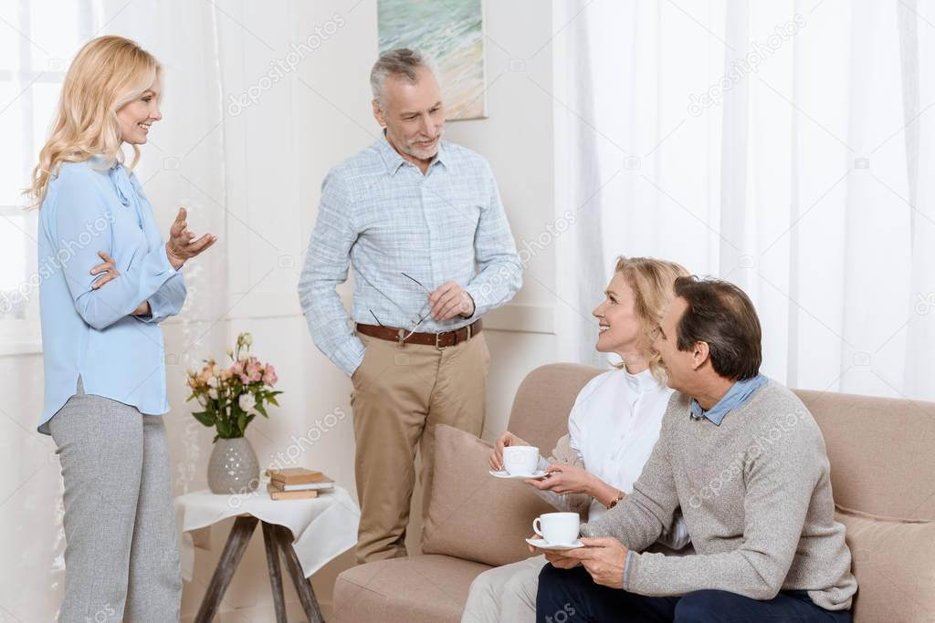 Senior men and women having a conversation while drinking tea on sofa