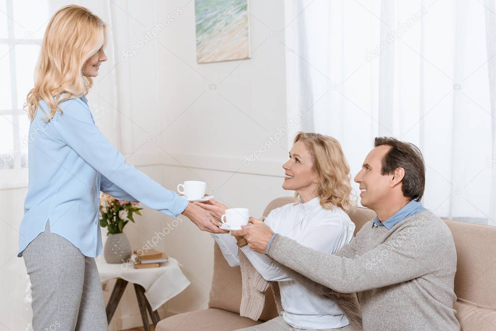 Middle aged man and women having a conversation while drinking tea on sofa