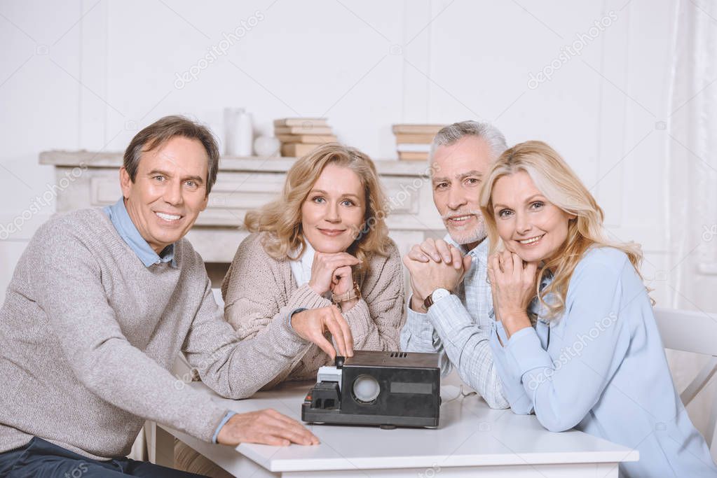 friends sitting at table while using projector on table   