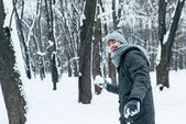portrét šťastný mladý muž si hraje s sníh v zimě parku